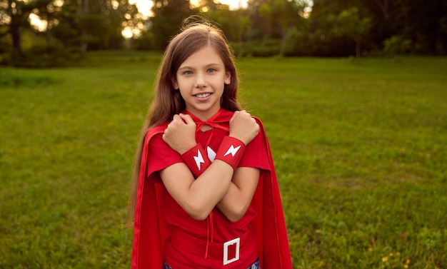 Garota feliz em traje de super-herói vermelho no parque