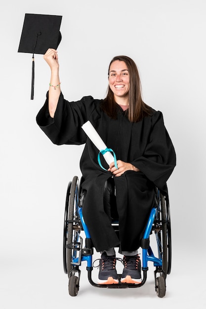 Garota feliz em uma cadeira de rodas segurando seu diploma