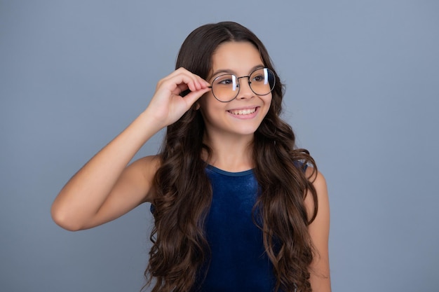 Garota feliz enfrenta emoções positivas e sorridentes Criança adolescente usando óculos no fundo cinza do estúdio Garota bonita de óculos
