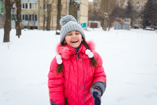 Garota feliz jogando em um playground no dia gelado de inverno.