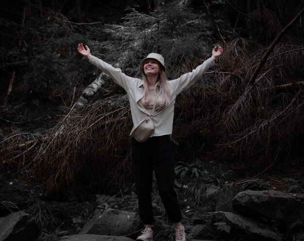 Garota feliz levantou as mãos e sorriu em um fundo de floresta