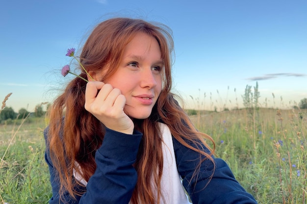 Garota feliz no campo no verão ao nascer ou pôr do sol curtindo a natureza