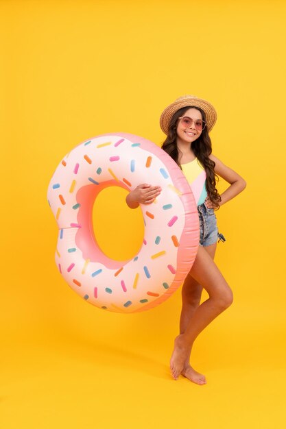 Garota feliz no chapéu de palha e óculos de sol anel de rosquinha inflável criança segura acessório de praia do anel de natação círculo inflável ativo infância verão criança fim de semana bronzeado férias de verão