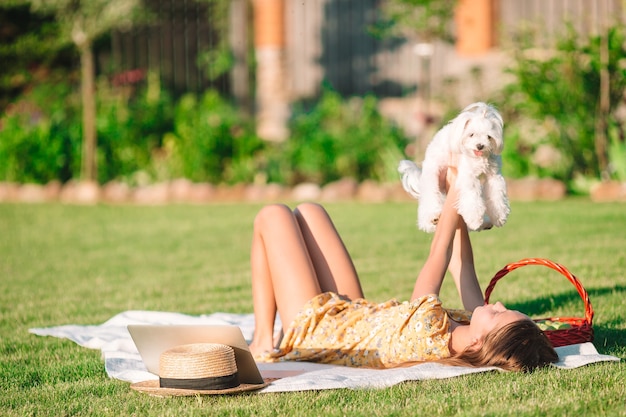 Garota feliz no piquenique brinca com cachorro branco na grama verde do parque