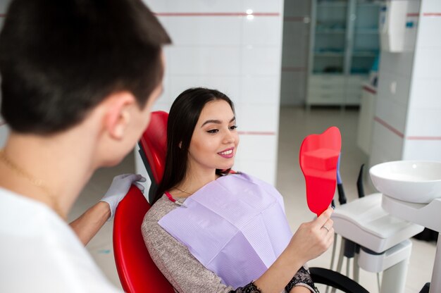 Garota feliz olhando no espelho para um sorriso na odontologia.