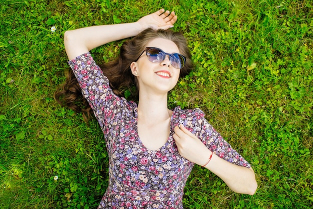 Garota feliz relaxando no gramado deitado de costas e olhando para o céu