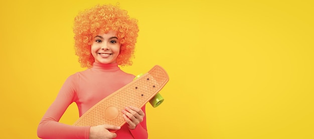 Garota feliz scater com cabelo laranja no sorriso poloneck rosa segurando pennyboard andando de skate Criança adolescente engraçada no cabeçalho de banner de cartaz de festa com espaço de cópia