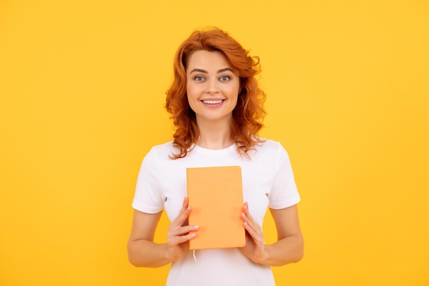 Garota feliz segura o planejador em fundo amarelo, educação.