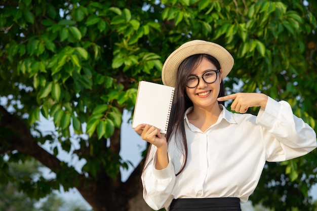 Foto garota feliz, segurando o caderno em branco com a natureza