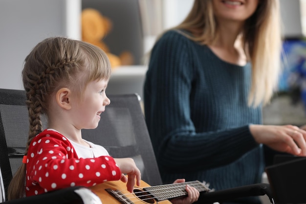 Garota feliz segurando violão e tocando música em um instrumento musical