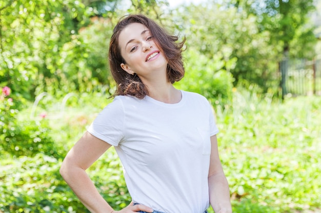 Garota feliz sorrindo ao ar livre. Mulher jovem e bonita morena com cabelo castanho, descansando no fundo do parque ou jardim verde.