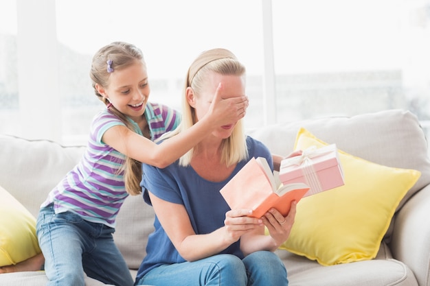 Garota feliz, surpreendendo a mãe com presente em casa