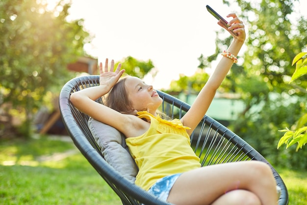 Garota feliz tira selfie no celular no parque ao ar livre