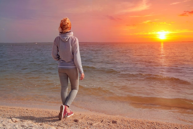 Garota fica de costas para o mar ao pôr do sol Viajar para a Europa Holanda