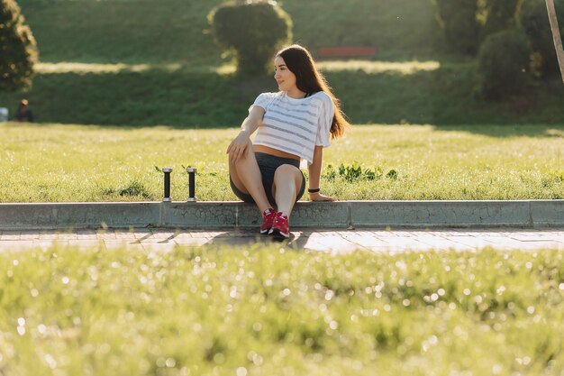 Garota fitness fazendo exercícios com halteres no pôr do sol na grama do lado de fora