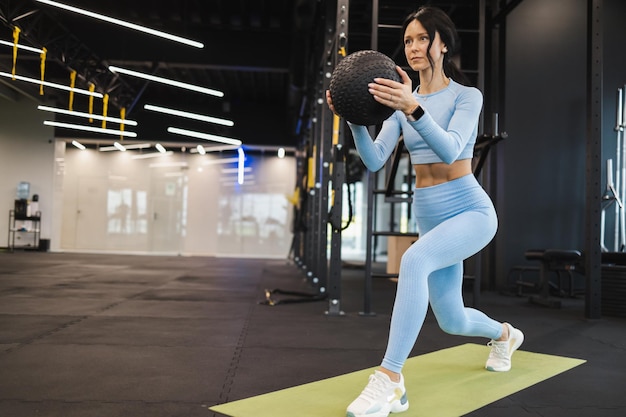 Garota fitness fazendo exercícios de pernas com bola médica