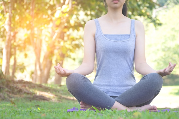 Garota fitness praticando yoga no parque com a luz do sol