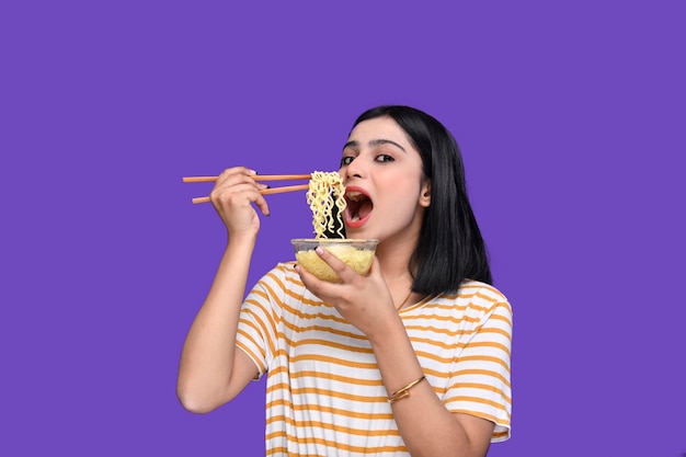 garota foodie comendo macarrão sobre fundo roxo modelo indiano do paquistanês