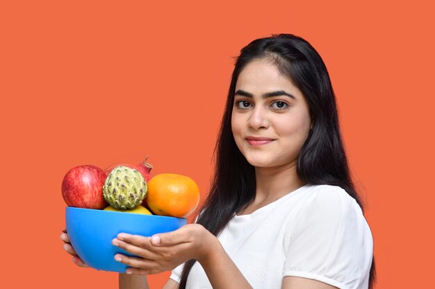 garota foodie vestindo camiseta branca sorrindo e segurando fruteira modelo indiano do paquistanês