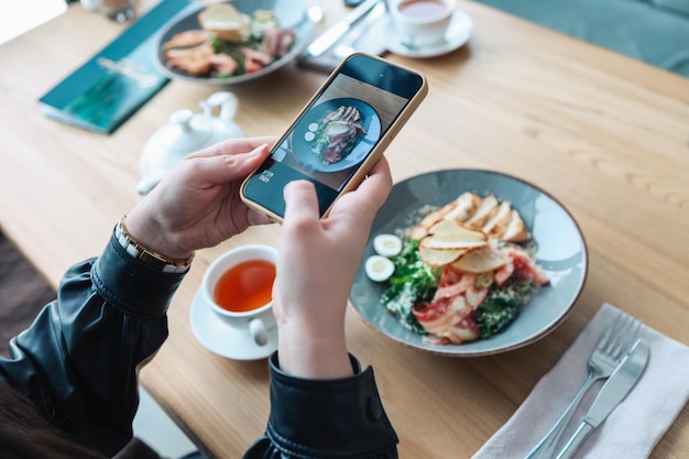 Garota fotografando comida em um restaurante