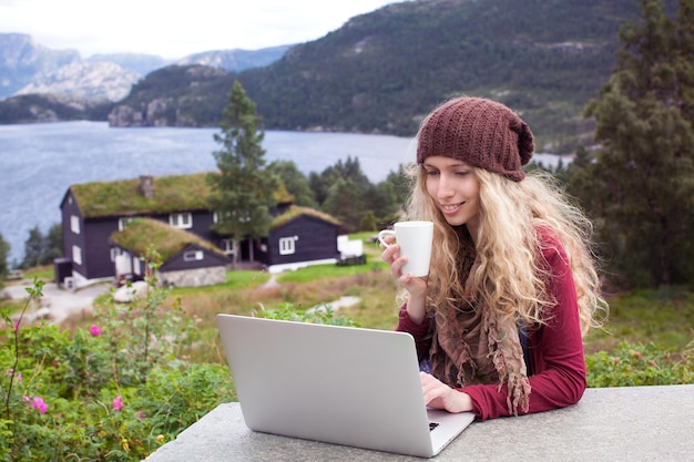 Garota freelance trabalhando no laptop na natureza e belas paisagens