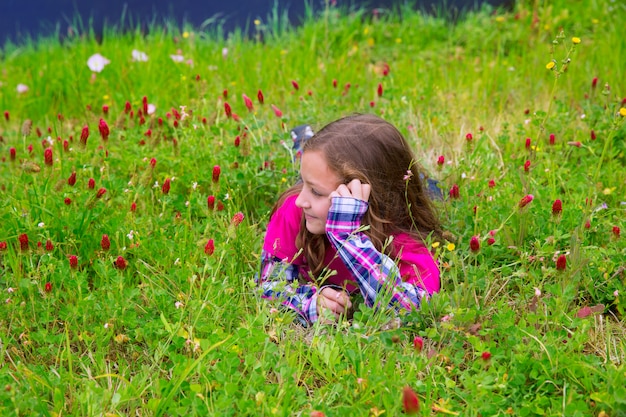 Garota garoto relaxado feliz em um prado de flores de primavera