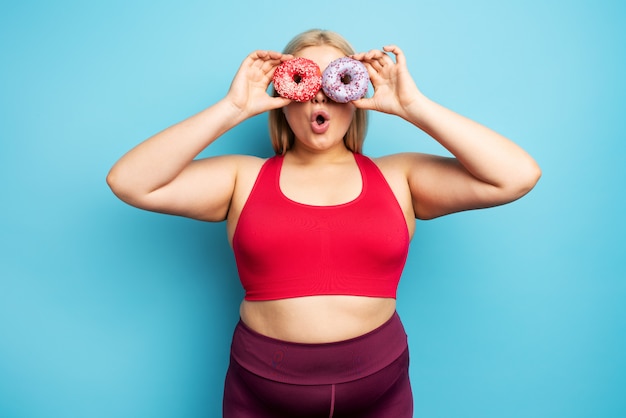 Garota gorda pensa em comer donuts em vez de fazer ginástica. conceito de indecisão e dúvida