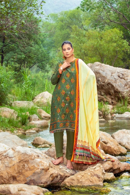 Garota gostosa de pés descalços nas rochas do lago na selva verde usando vestido tradicional completo