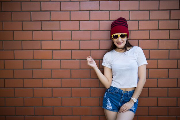 Garota hipster asiática de retrato no fundo da parede de tijolosEstilo de vida do povo da tailândia