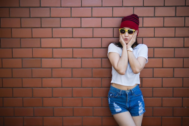 Garota hipster asiática de retrato no fundo da parede de tijolosEstilo de vida do povo da tailândia