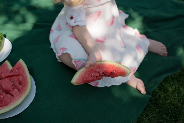 Garota irreconhecível come melancia em um parque de verão, close-up