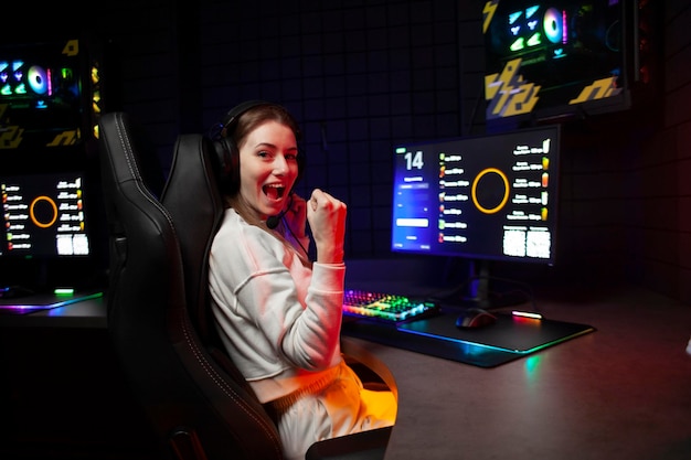 Garota jogadora senta em um computador e grita no monitor mulher louca se alegra com a vitória