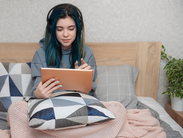 Garota jovem adolescente com cabelo azul, tablet e fones de ouvido