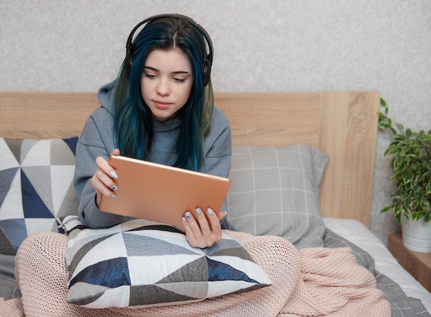 Garota jovem adolescente com cabelo azul, tablet e fones de ouvido