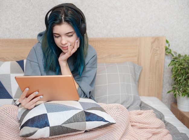 Garota jovem adolescente com tablet de cabelo azul e fones de ouvido