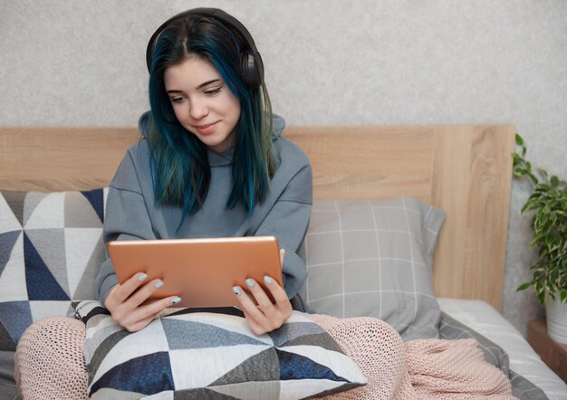 Garota jovem adolescente com tablet de cabelo azul e fones de ouvido