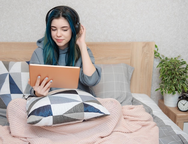 Garota jovem adolescente com tablet de cabelo azul e fones de ouvido