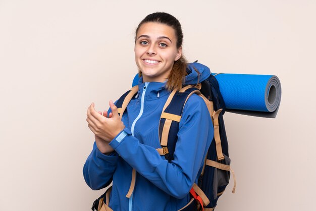 Garota jovem alpinista com uma mochila grande aplaudindo