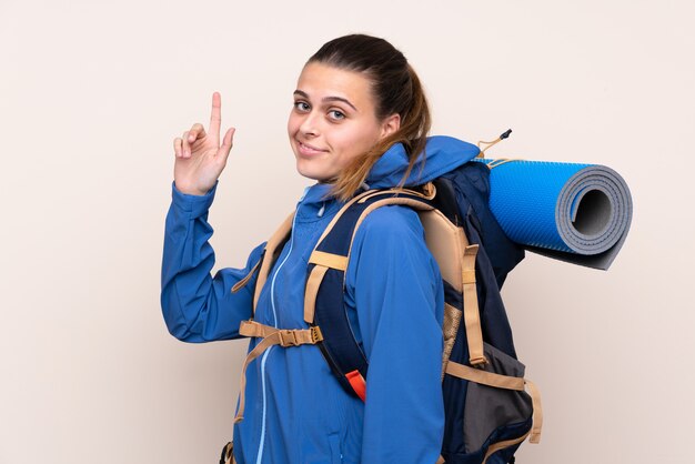 Garota jovem alpinista com uma mochila grande, apontando com o dedo indicador uma ótima idéia