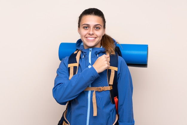 Garota jovem alpinista com uma mochila grande comemorando uma vitória