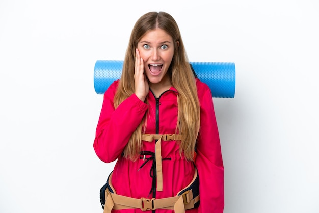 Garota jovem alpinista com uma mochila grande sobre fundo branco isolado com surpresa e expressão facial chocada