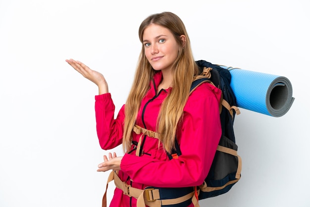 Garota jovem alpinista com uma mochila grande sobre fundo branco isolado, estendendo as mãos para o lado para convidar para vir