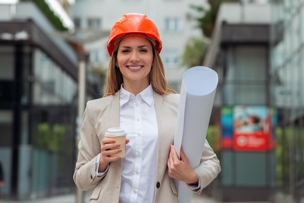 Garota jovem arquiteto segurando plantas e bebendo café na cidade