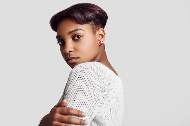 Garota jovem bonita hipster preto com cabelo curto na camisola branca