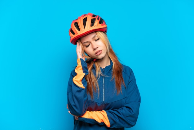 Garota jovem ciclista isolada em um fundo azul com dor de cabeça