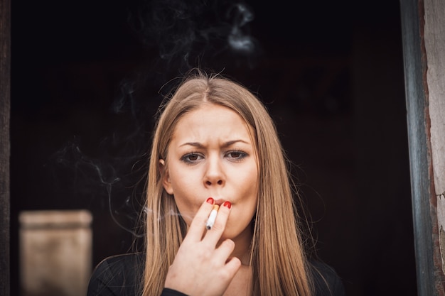 Garota jovem e atraente fumando um charuto