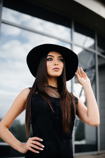 Garota jovem e sexy elegante posando em frente a um centro de negócios de preto