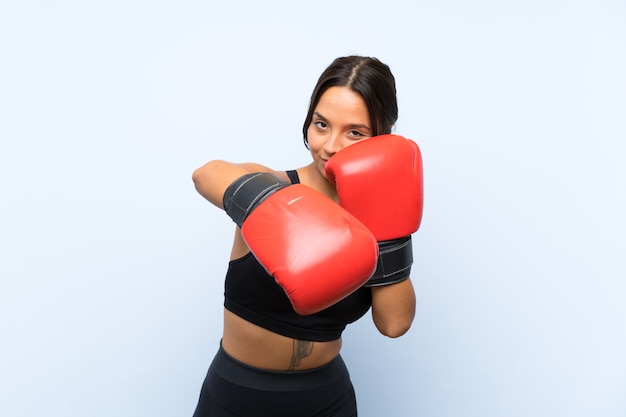 Garota jovem esporte com luvas de boxe sobre parede azul isolada