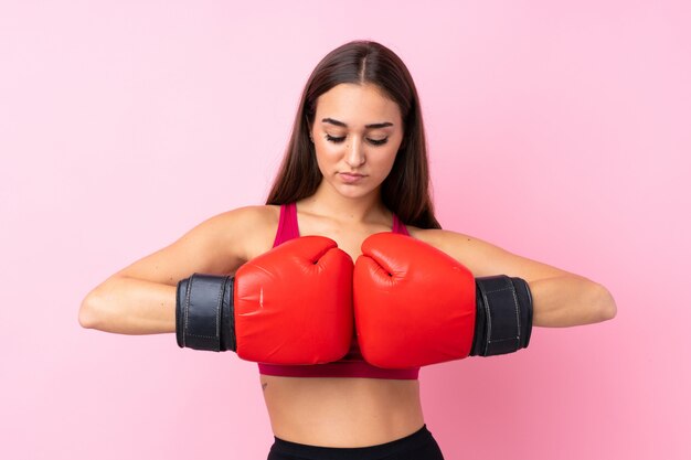 Garota jovem esporte sobre rosa isolado com luvas de boxe