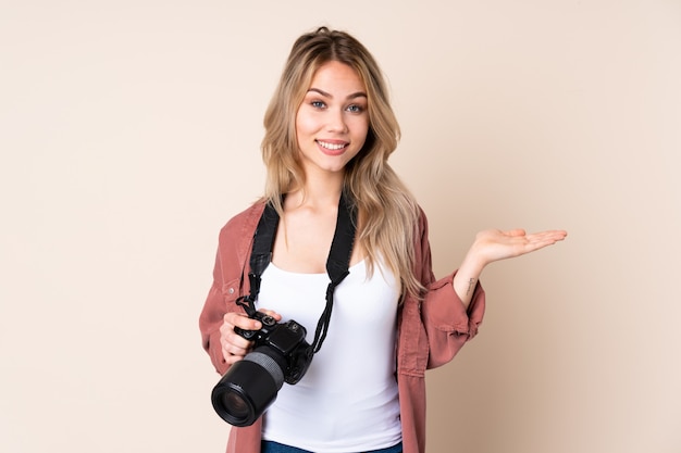 Garota jovem fotógrafo parede segurando espaço em branco na palma da mão para inserir um anúncio